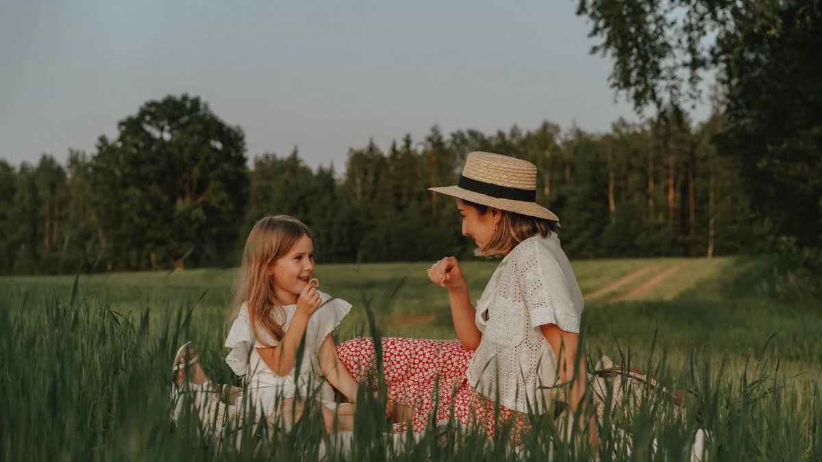 A loving moment shared between mother and daughter during a picnic in a lush field.